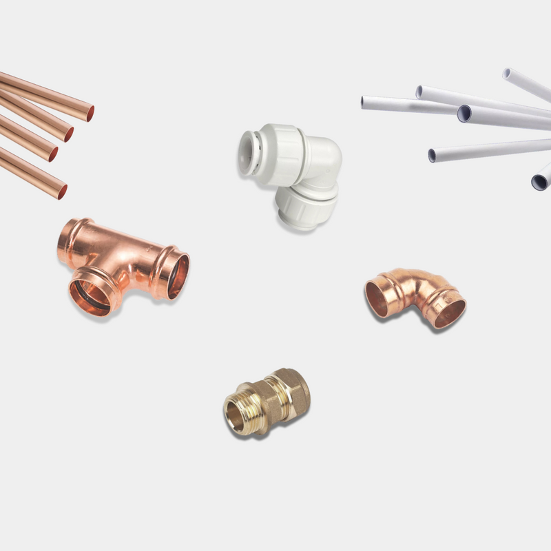 Collection of copper and white plumbing pipes and fittings on a light gray background