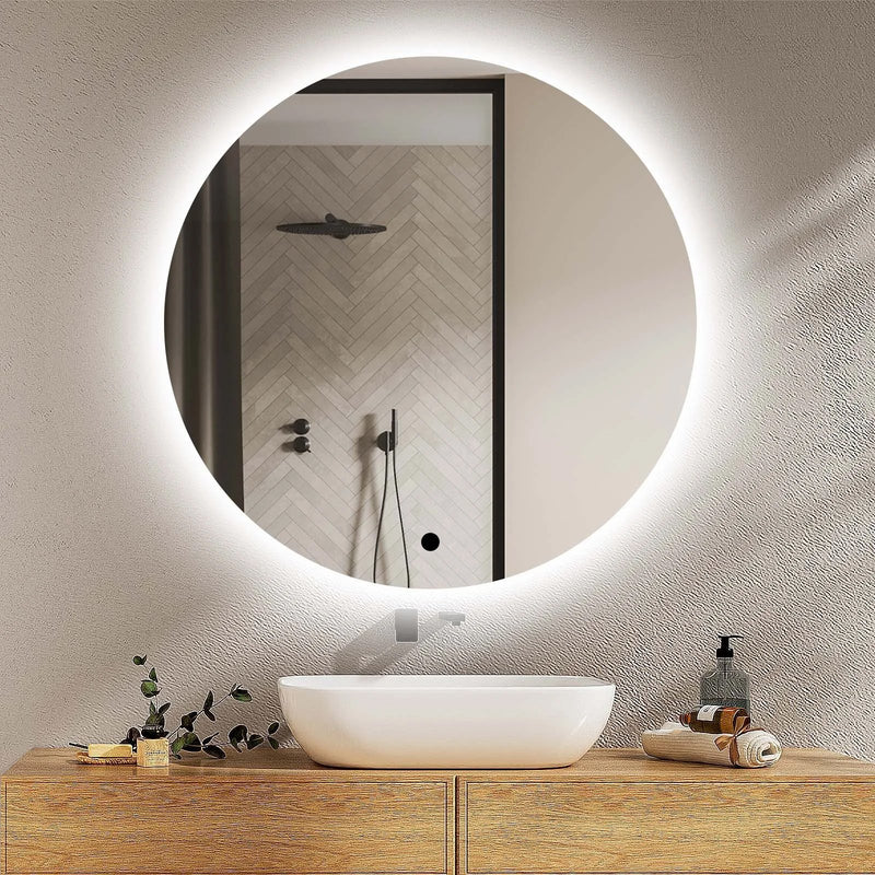 Round illuminated LED bathroom mirror above a wooden vanity with a white round sit on basin