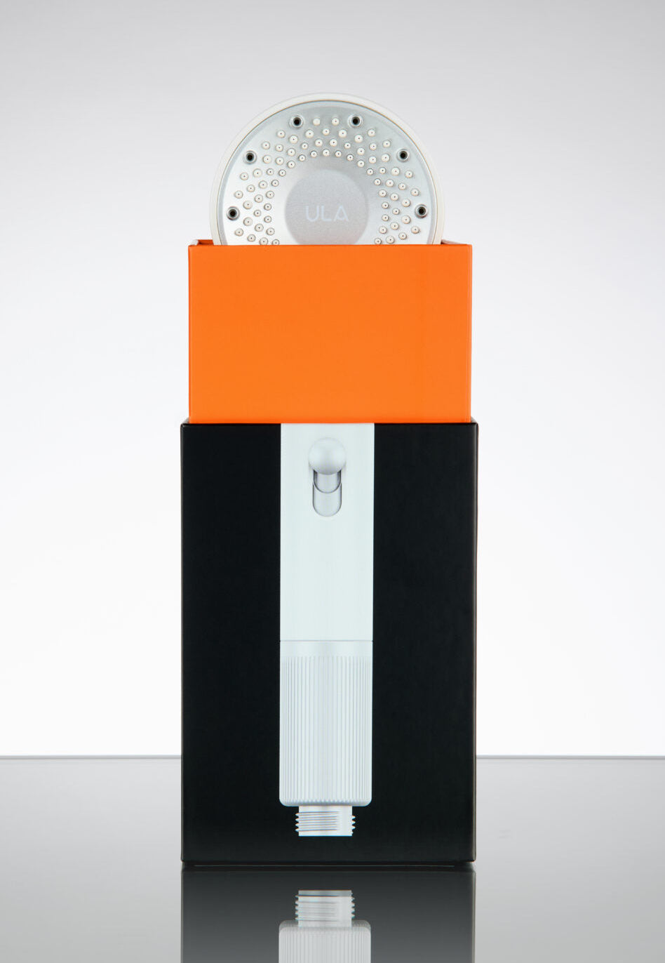 Black and orange device with a circular component on a reflective surface