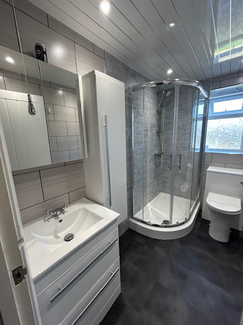 Modern bathroom with glass shower enclosure and white bathtub.